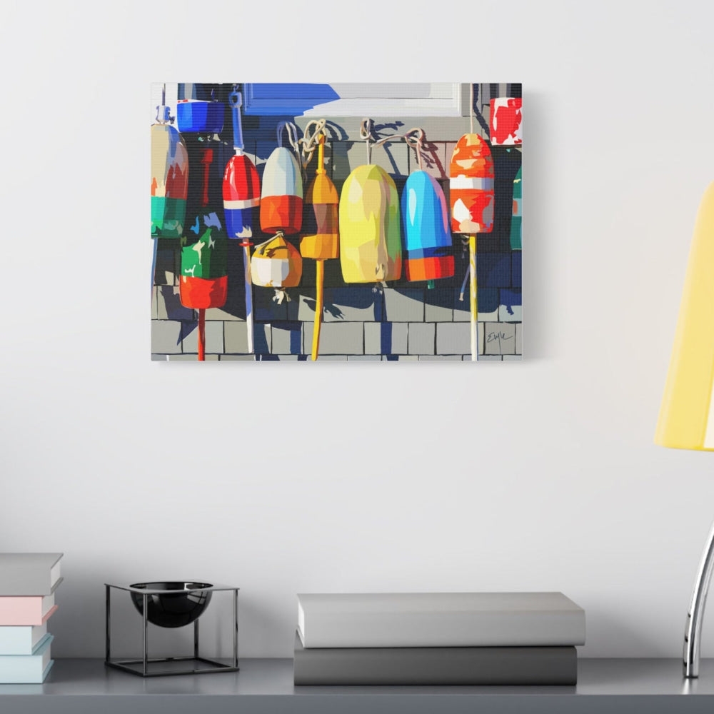 Canvas print of colorful buoys on a wall above a desk with books and a lamp.