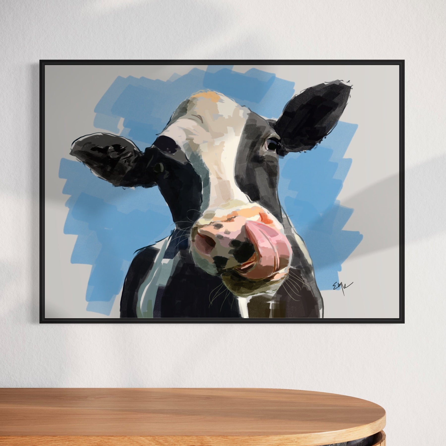 Framed painting of a cow's face on a wall above a wooden cabinet.