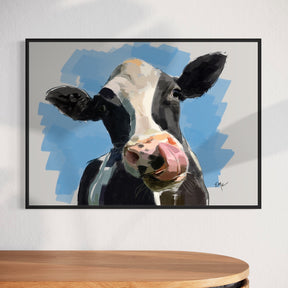 Framed painting of a cow's face on a wall above a wooden cabinet.