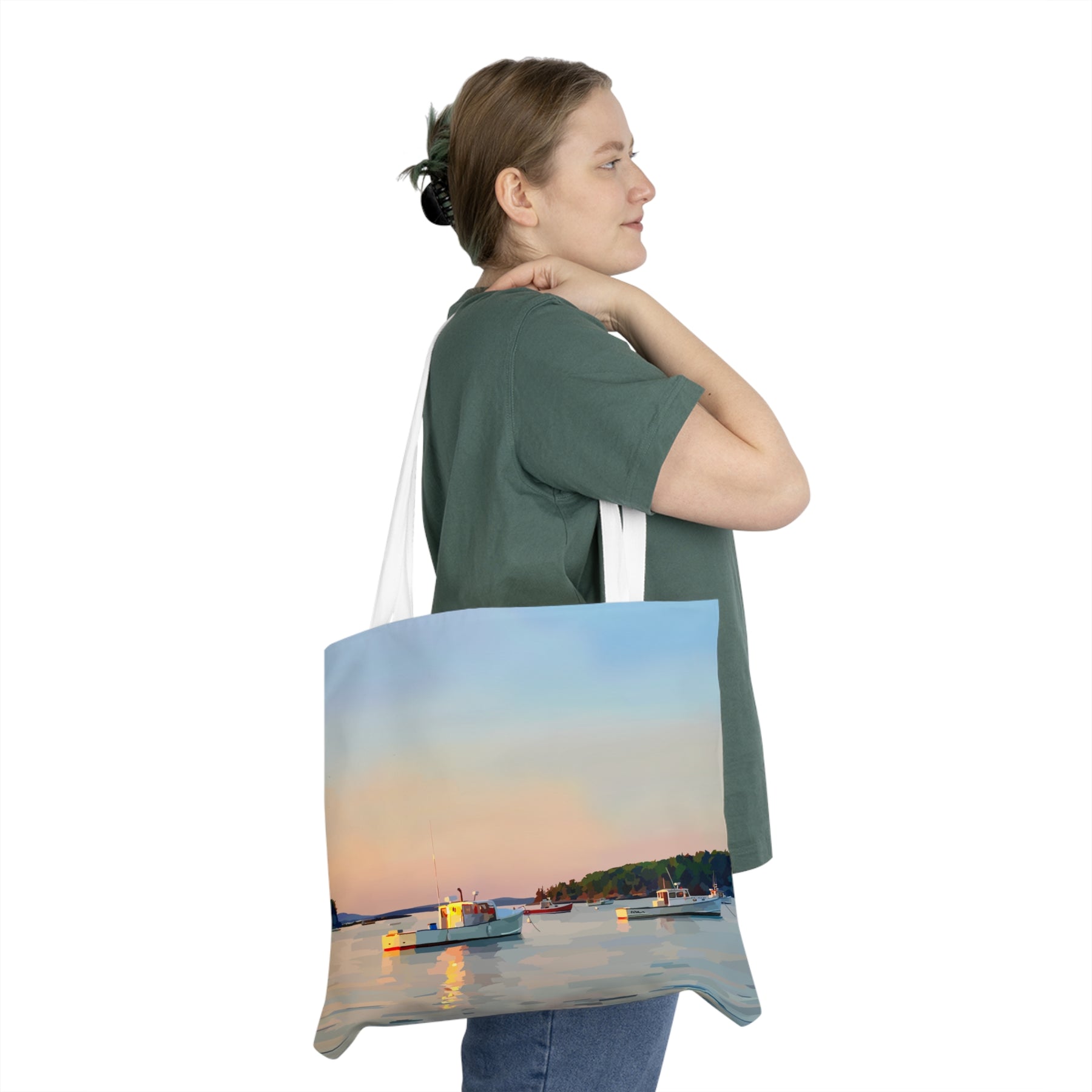 Woman carrying a tote bag with a scenic design of a sunset over water and boats.